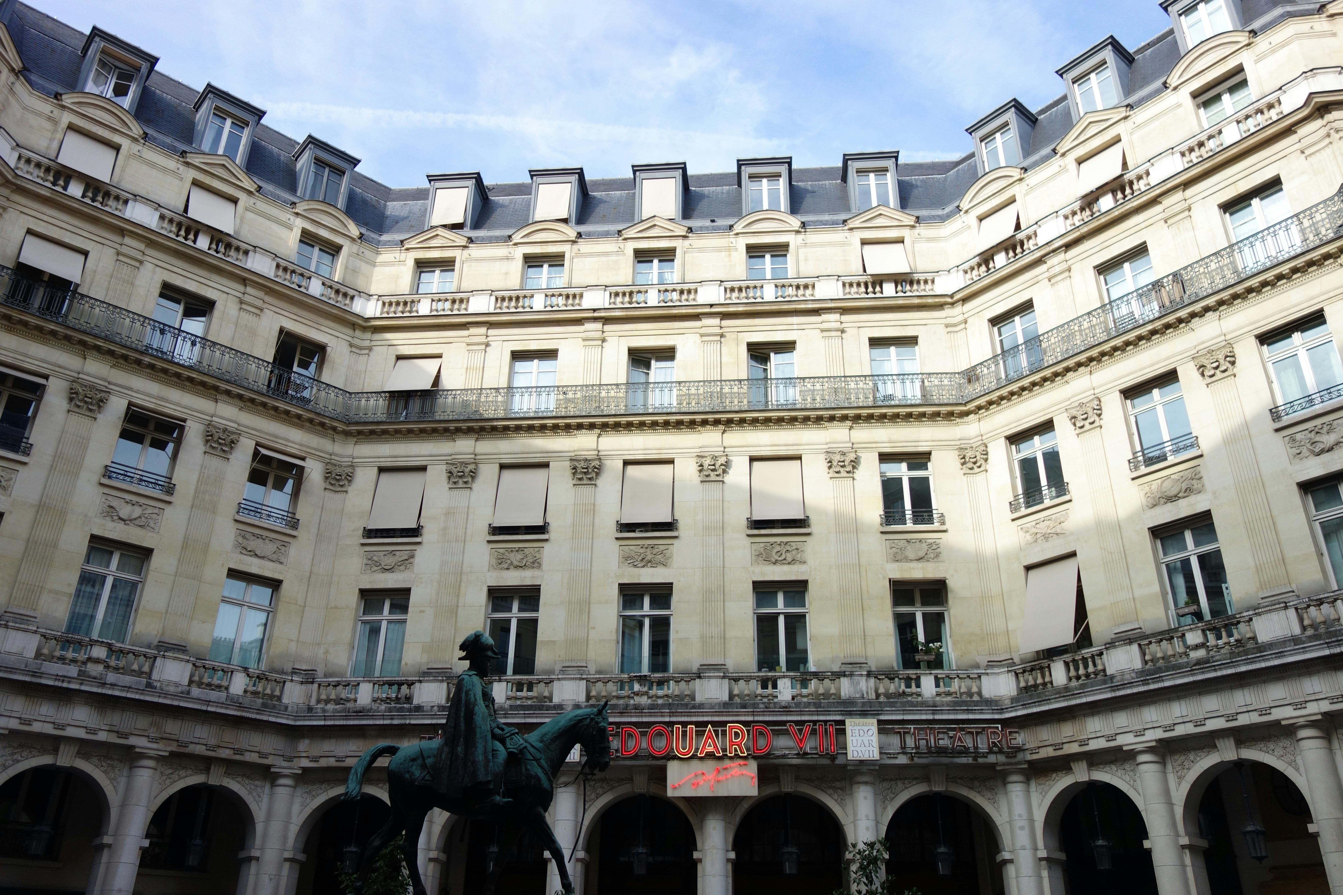 Free Elegant architecture of Edouard VII Theatre courtyard in Paris with a statue at the center. Stock Photo