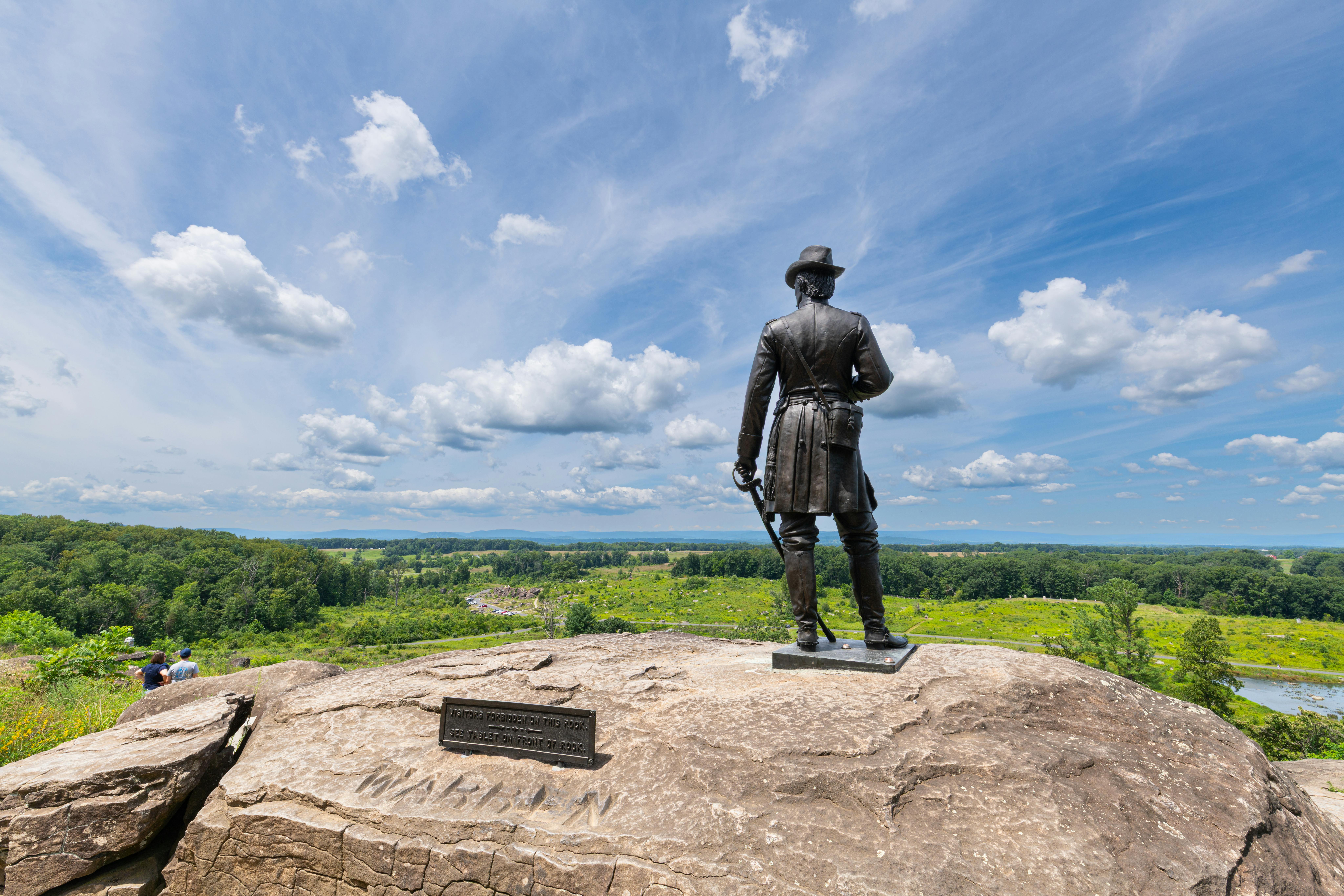 War memorial statue overlooking Gettysburg battlefield under a blue sky.