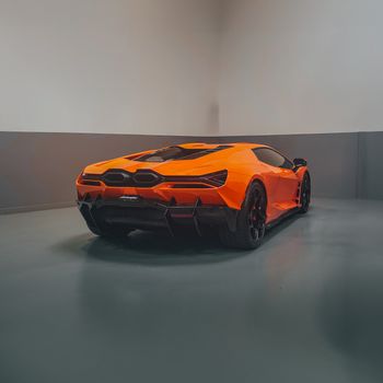 Captivating orange luxury sports car displayed indoors, highlighting sleek design and modern elegance.