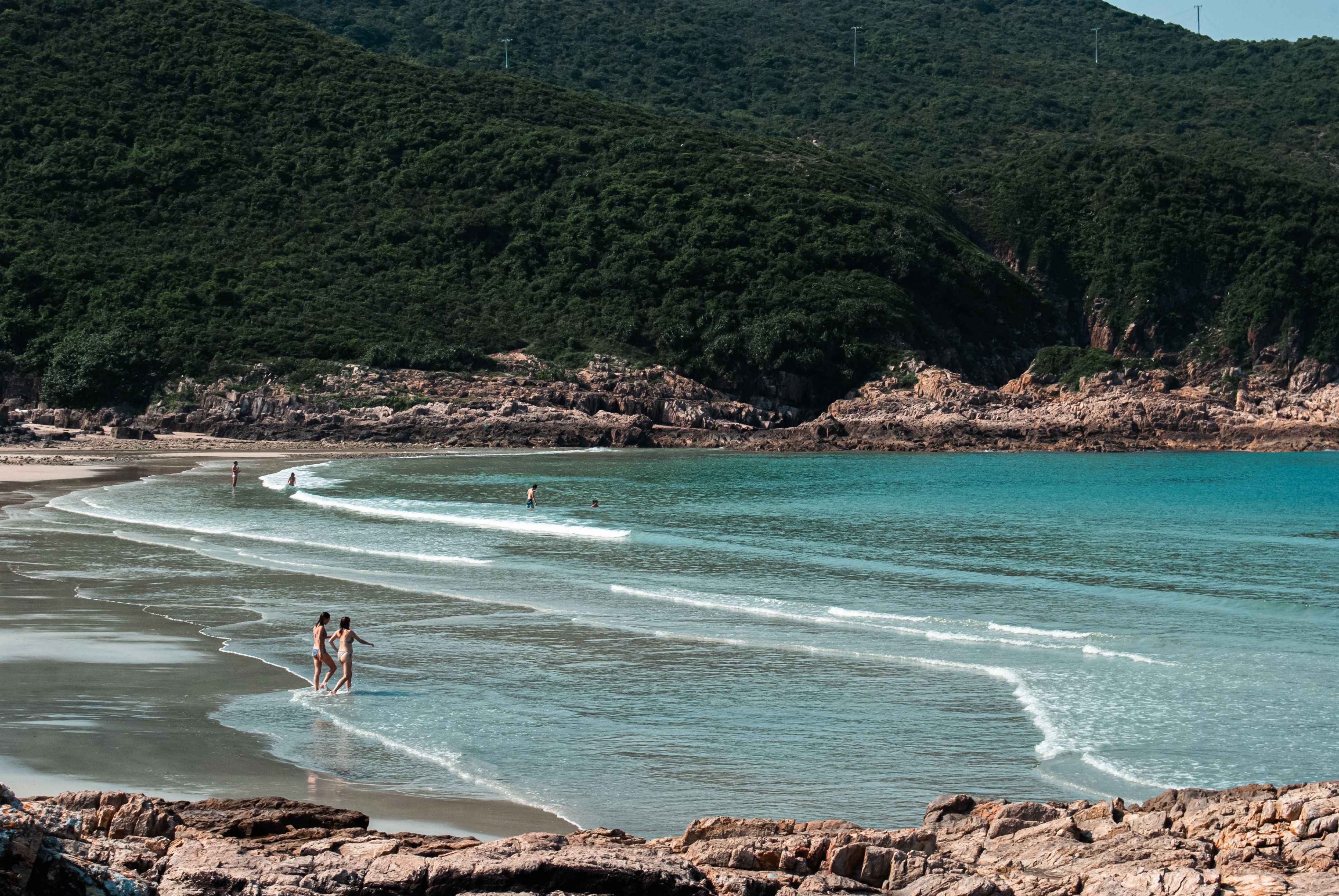 Peaceful summer day at a serene beach with swimmers enjoying the waves.