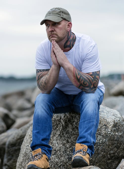 Man Sitting on Gray Rock on Selective Focus Photo