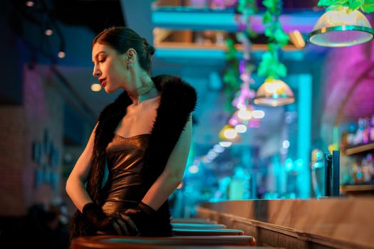 A sophisticated woman in a modern bar with neon lighting, exuding elegance and style.