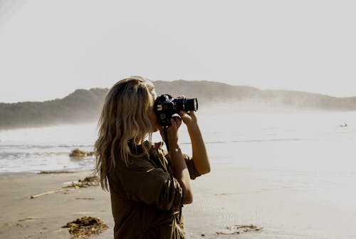 Free Woman Holding A Black Dslr Camera And Taking Pictures Stock Photo