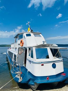 White and blue passenger boat docked on a sunny day by the river. — photo by Vitaliy Bratkov