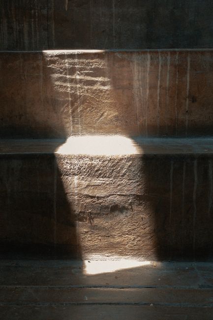 Close-up of sunlight streaming on textured stone steps, creating a dramatic shadow play.