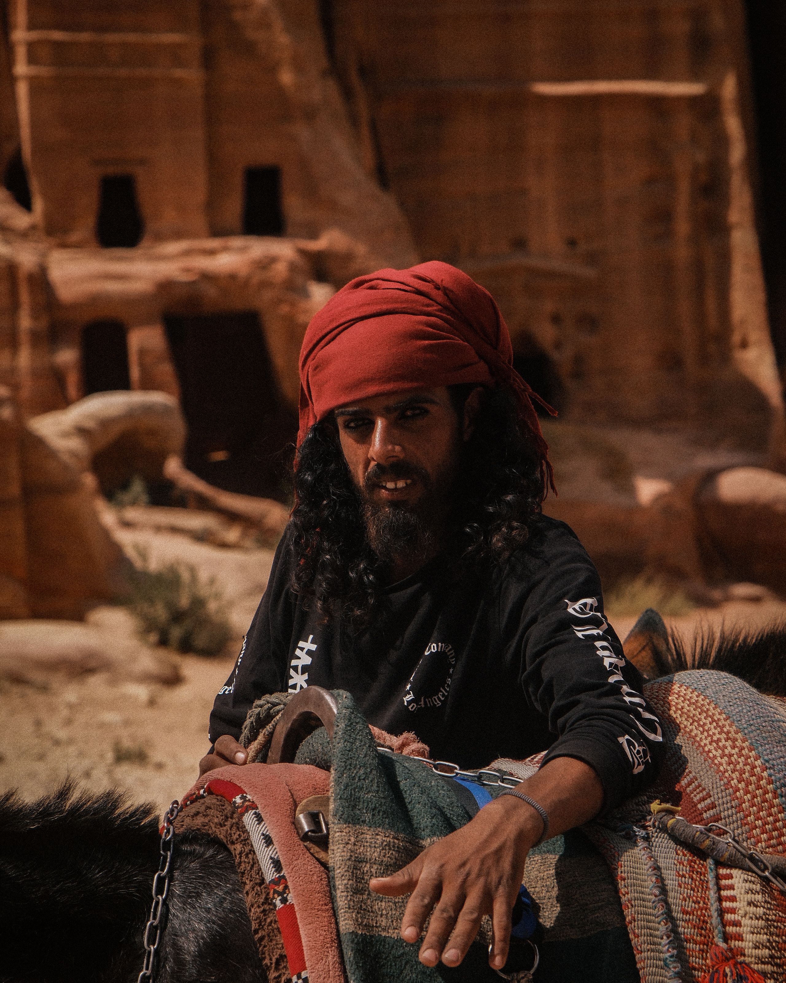 A Bedouin man in traditional attire with a camel at Petra's ancient ruins, Jordan.