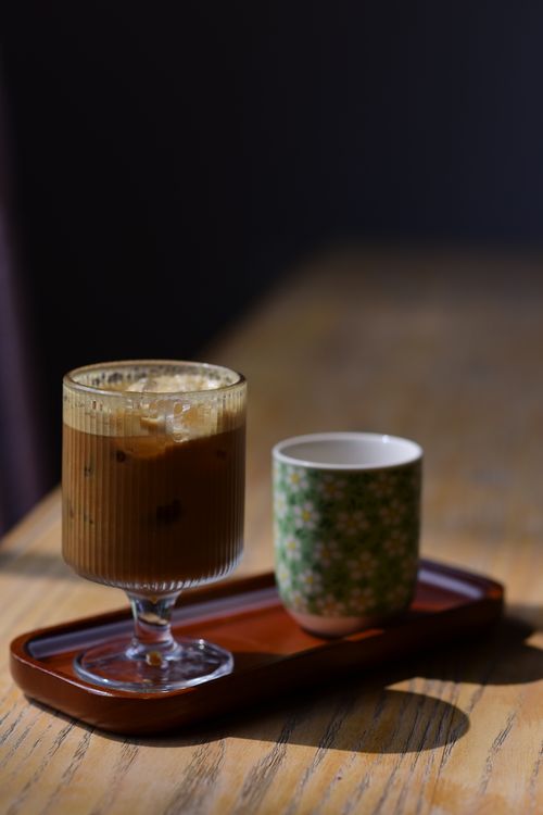 Free Aesthetic display of iced coffee and green tea cup on a wooden tray in warm sunlight. Stock Photo