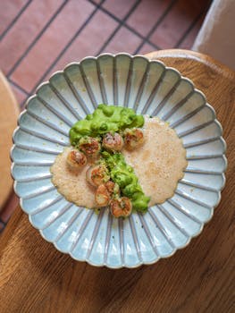 Gourmet scallops artistically plated with vibrant green sauce and foam.
