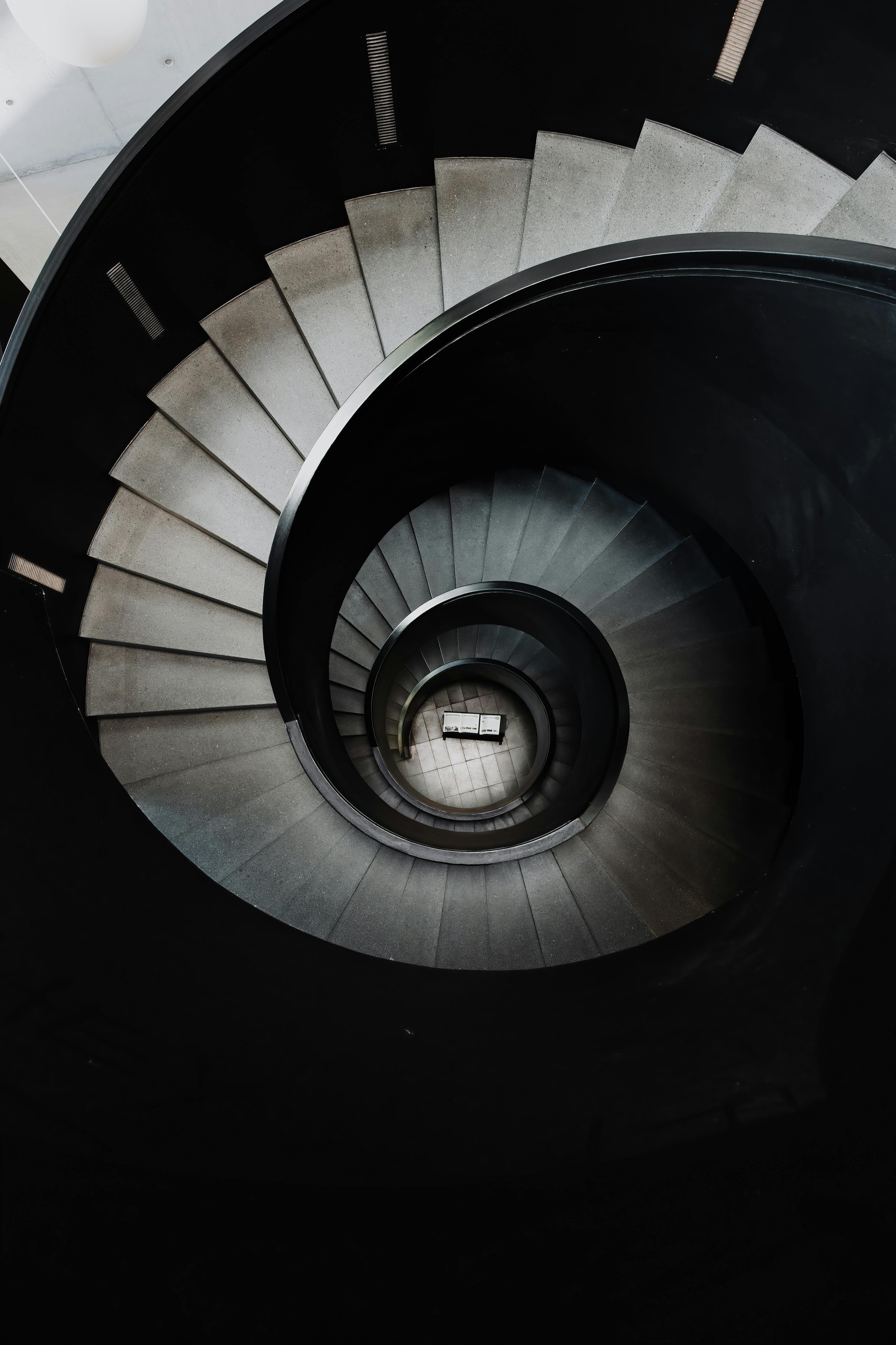 Artistic photo of a spiral staircase with dramatic shadows creating a mesmerizing pattern.
