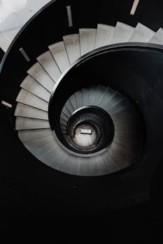 Artistic photo of a spiral staircase with dramatic shadows creating a mesmerizing pattern.