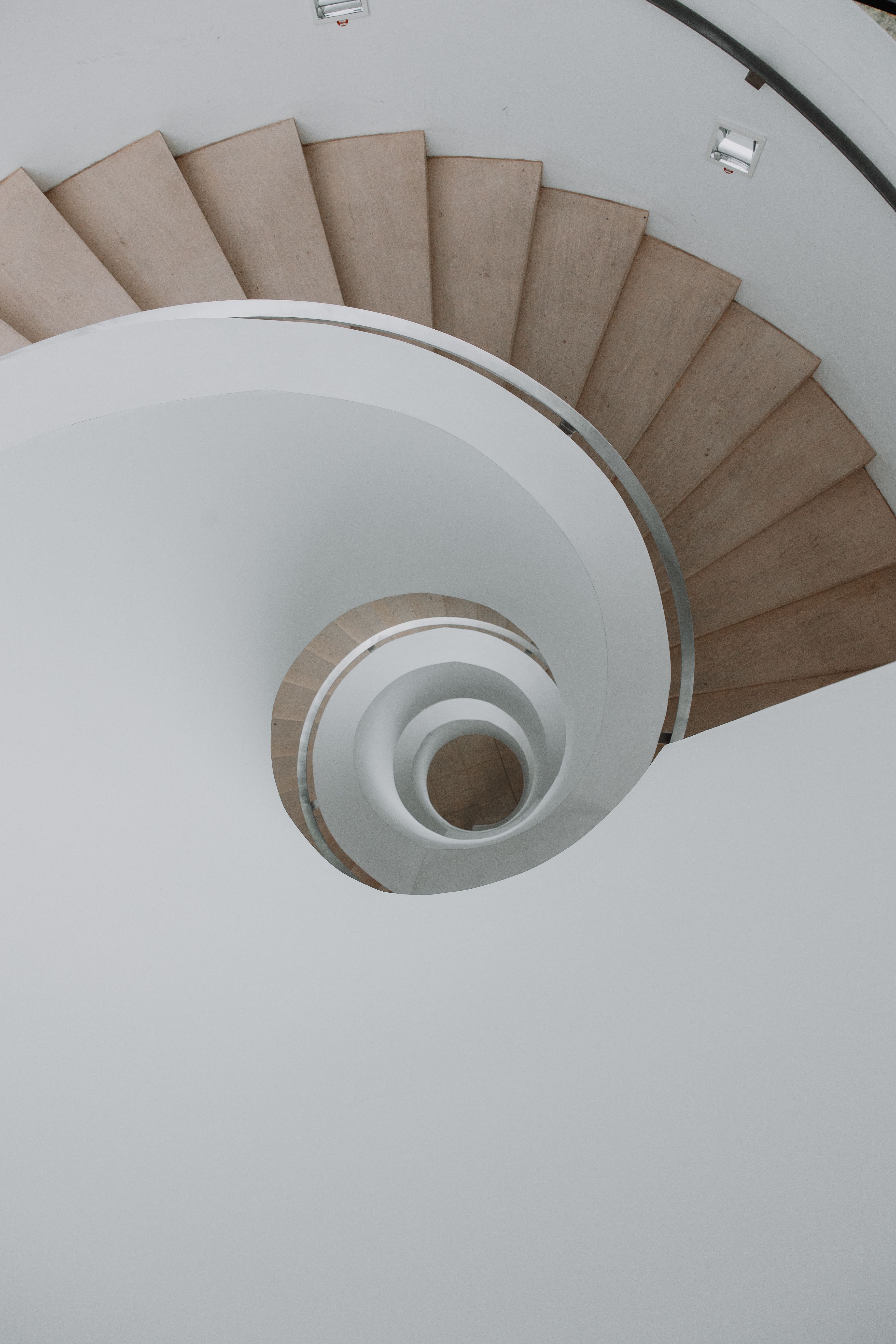 A captivating top view of a modern spiral staircase with natural wood tones, perfect for architectural inspiration.