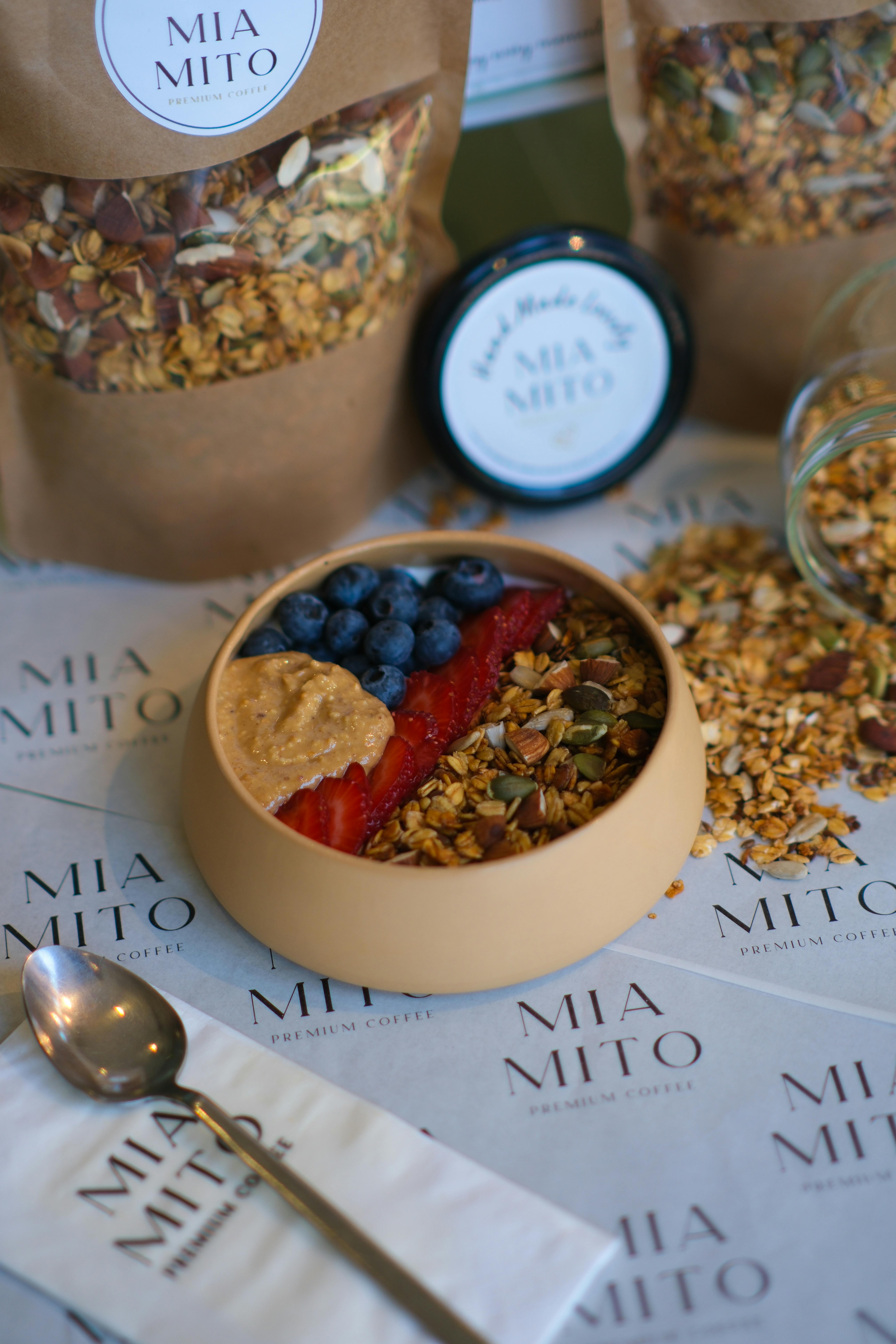 Colorful breakfast bowl with granola, strawberries, blueberries, and nut butter.