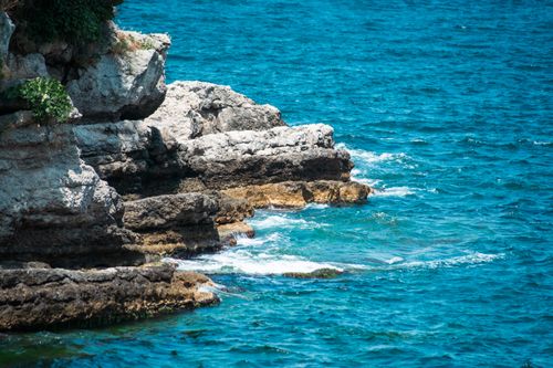 Free Explore the vibrant rocky coastline with clear blue seas and white waves. Stock Photo