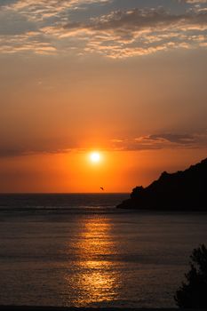 Breathtaking sunset over a calm ocean, highlighting warm hues and silhouettes.