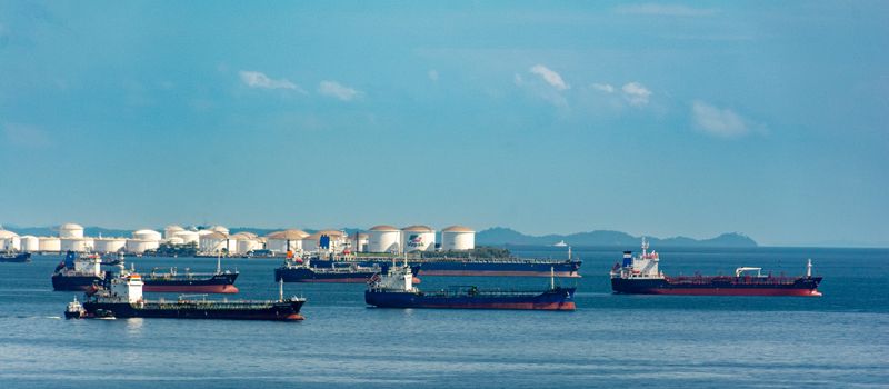 原油輸入の増加を示す、港湾に停泊する貨物船と原油タンク群のイメージ