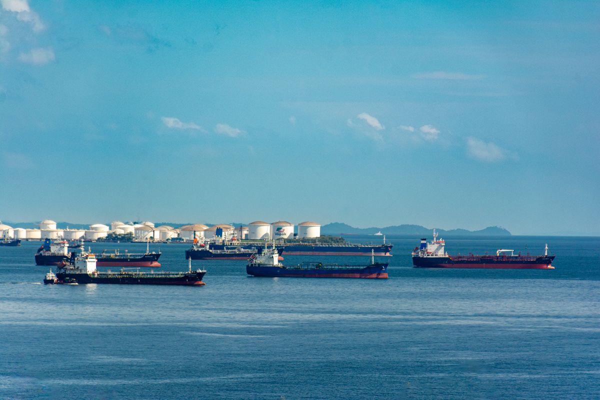 Fleet of cargo ships docked near oil storage tanks