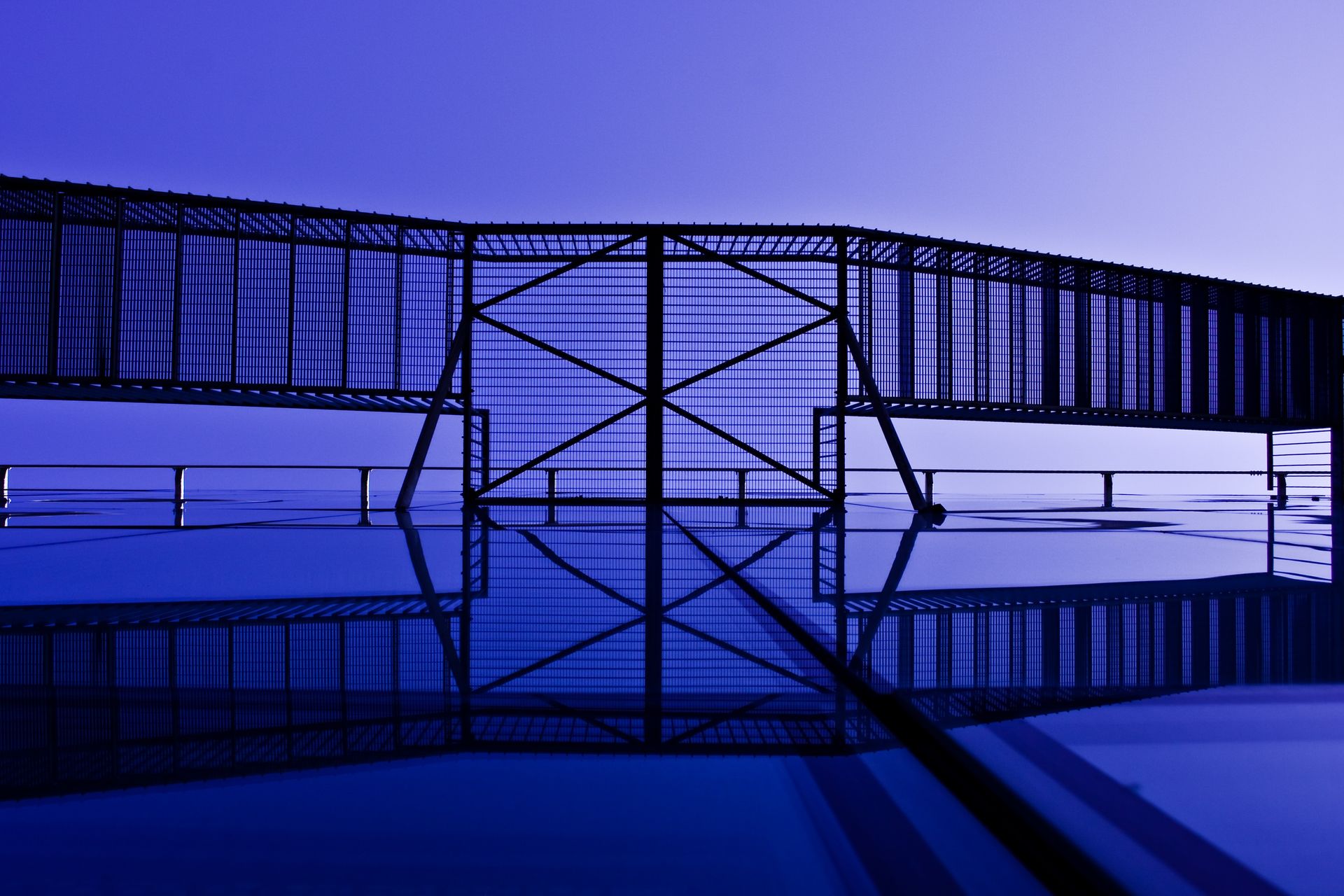 Abstract view of modern architectural elements with striking reflections and blue tones.