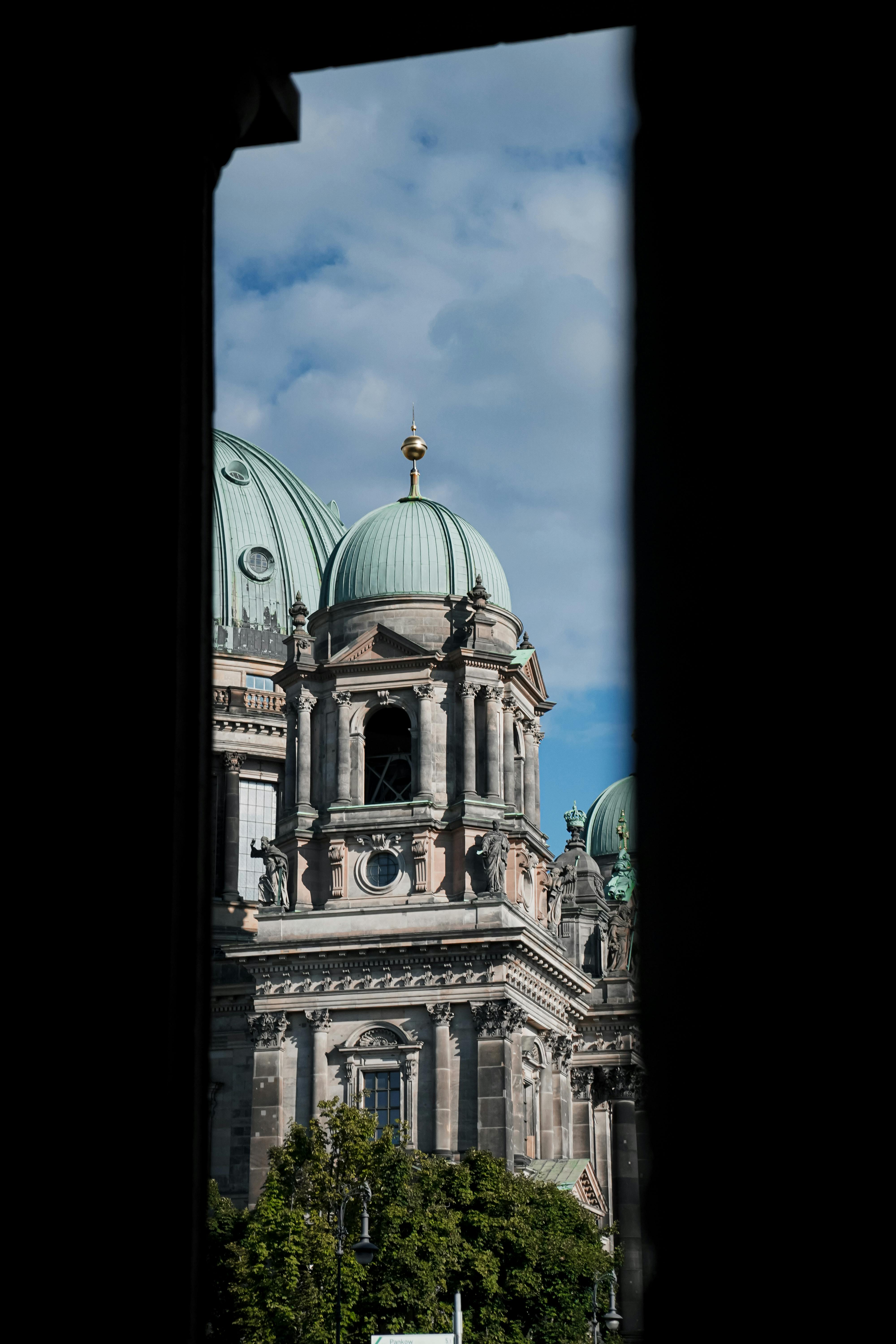 Captured through a window, showcasing the stunning architecture of Berlin Cathedral on a clear day.