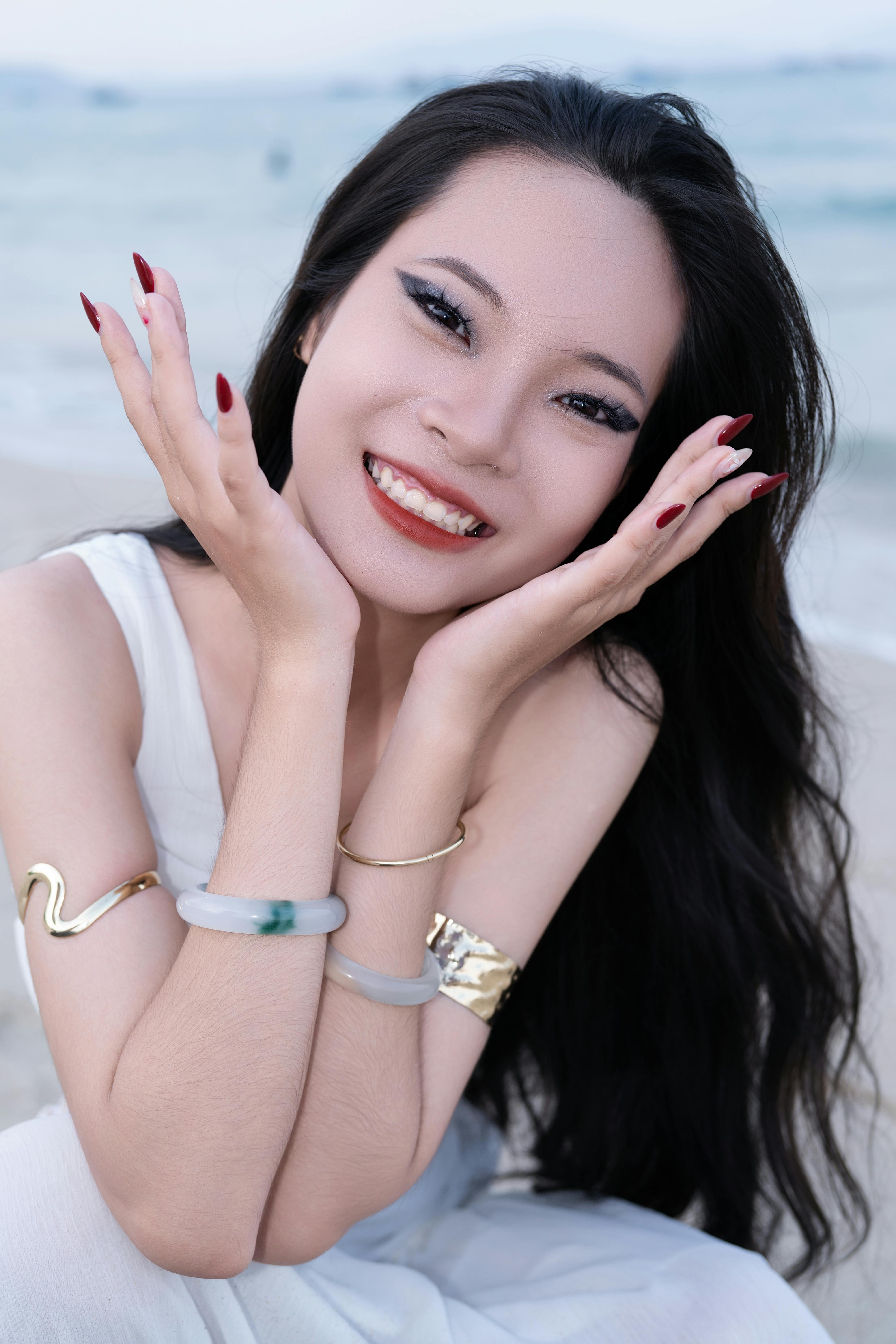 Smiling woman in white dress and jewelry enjoying sunny beach day.
