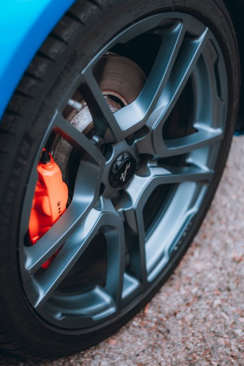 Free Detailed shot of a sleek alloy wheel and orange brake caliper on a blue car. Stock Photo