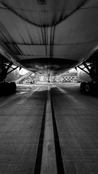 Underneath view of a large airplane on the tarmac in black and white.