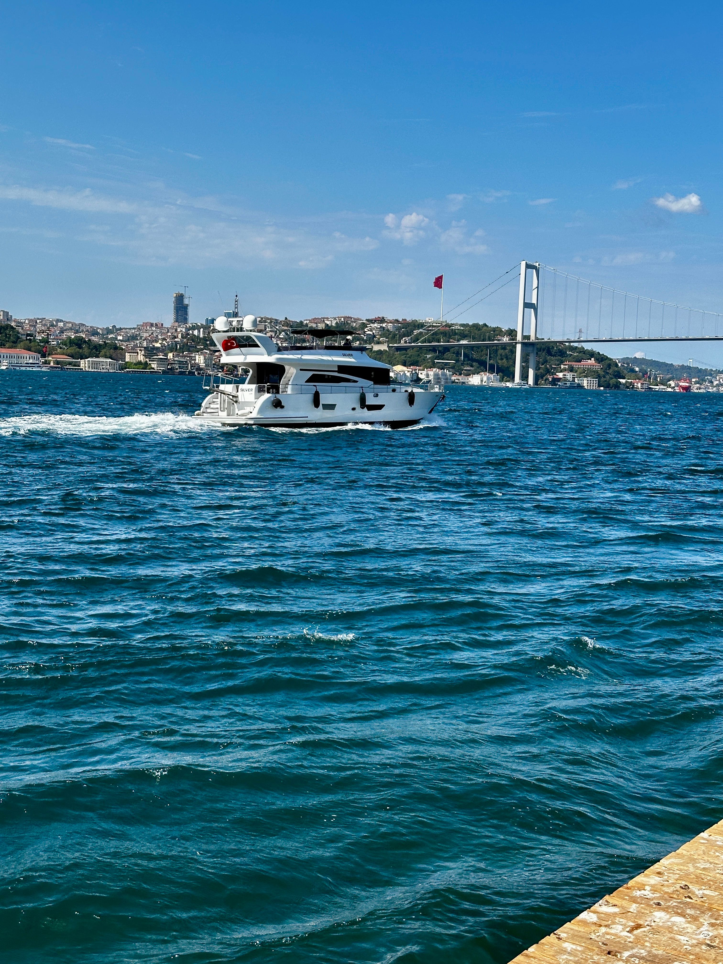 Free A luxury yacht cruises on Istanbul's Bosphorus with a bridge view on a sunny day. Stock Photo