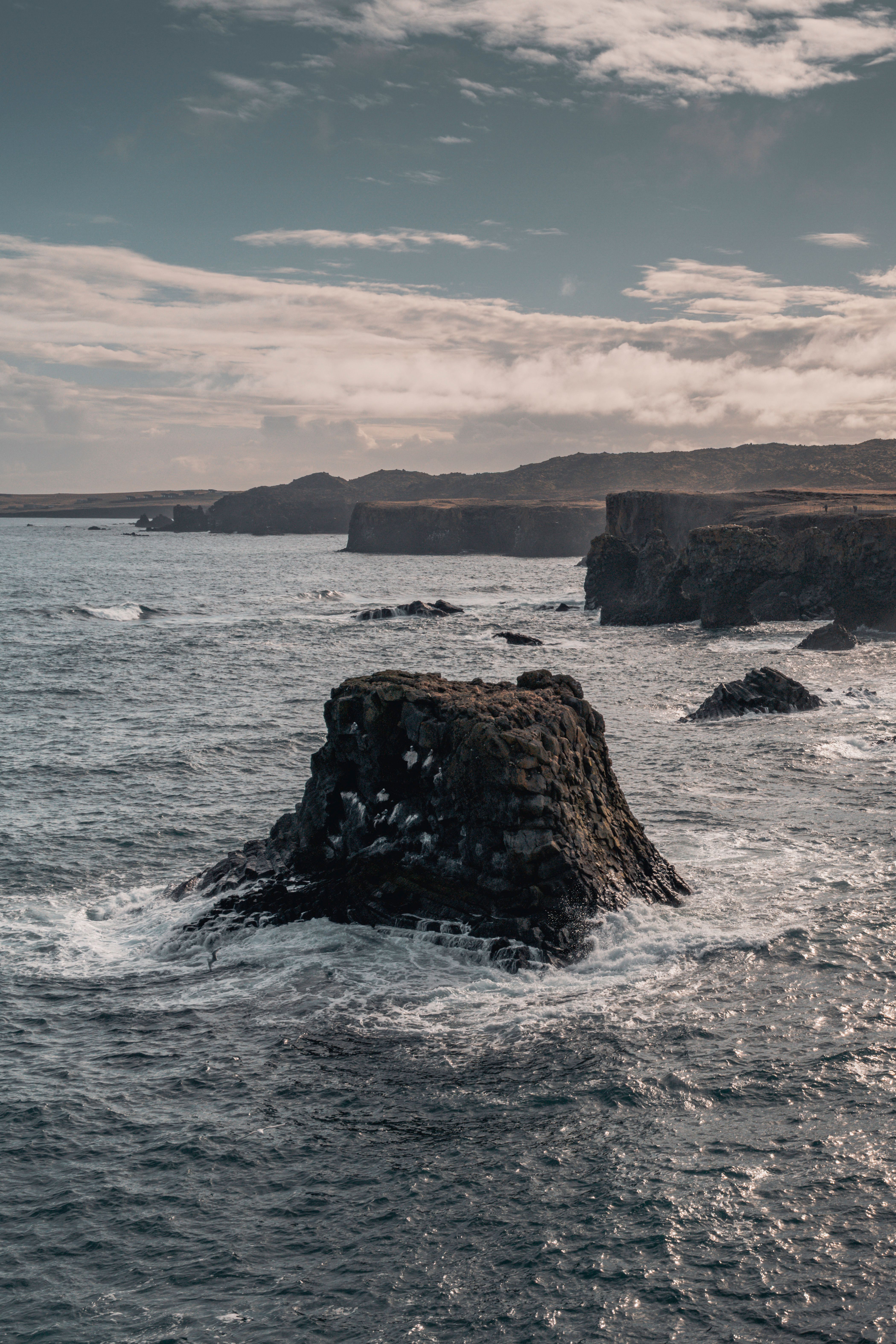 Breathtaking view of Iceland's rugged cliffs and ocean waves under a cloudy sky.