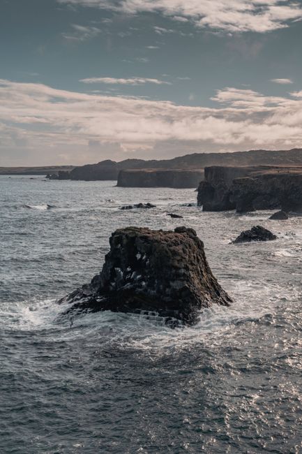 Breathtaking view of Iceland's rugged cliffs and ocean waves under a cloudy sky.