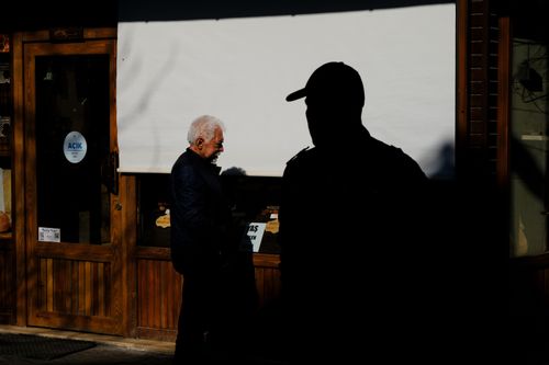 Free A shadowy silhouette contrasts with an elderly man outside a store in Bursa, Turkey. Stock Photo
