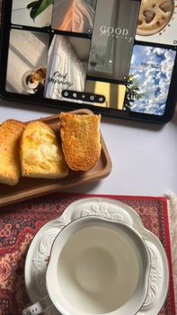 Cozy breakfast scene with buttered toast, tea cup, and tablet on a stylish table setting.