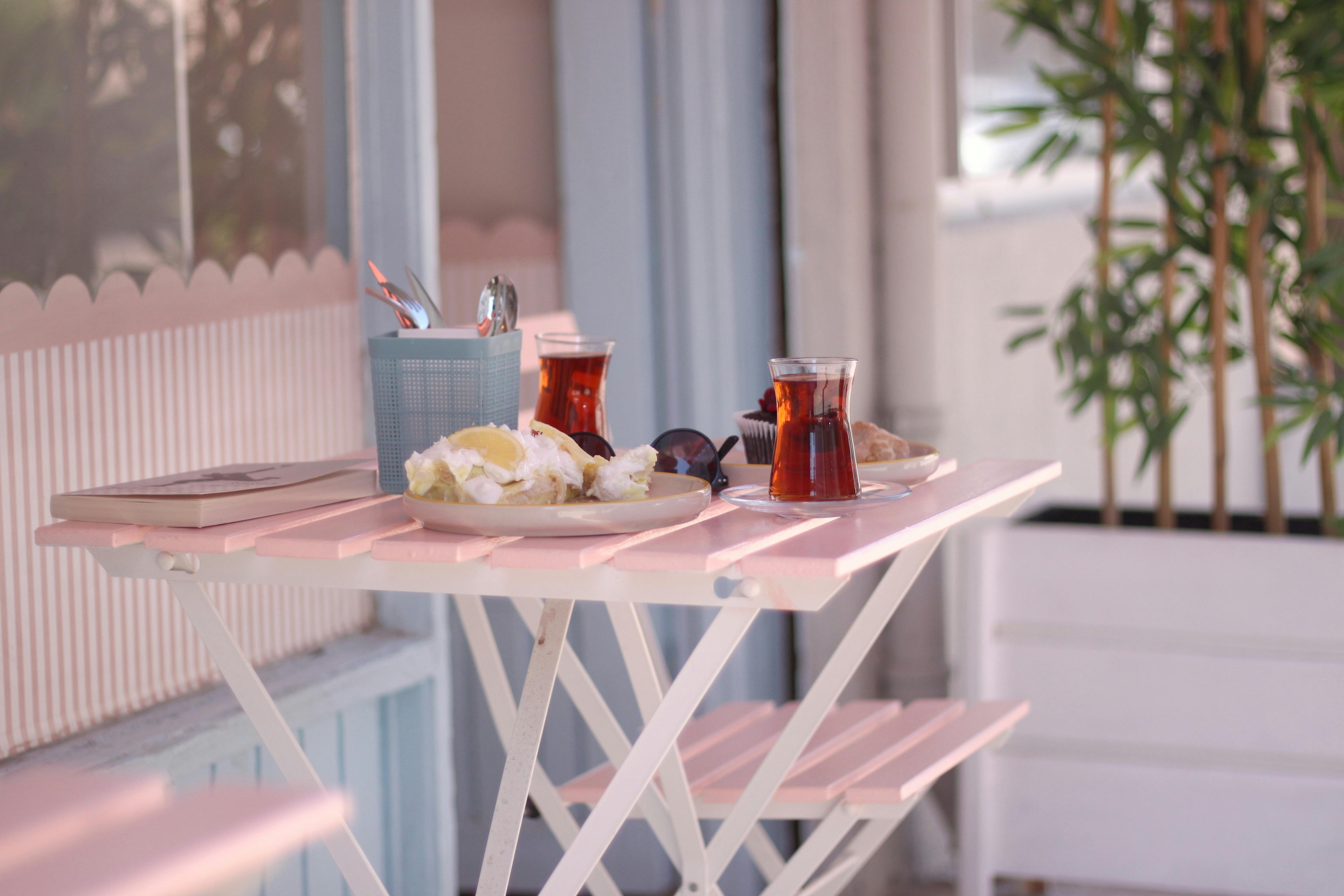 Charming outdoor café setting with tea and snacks on a pastel table.