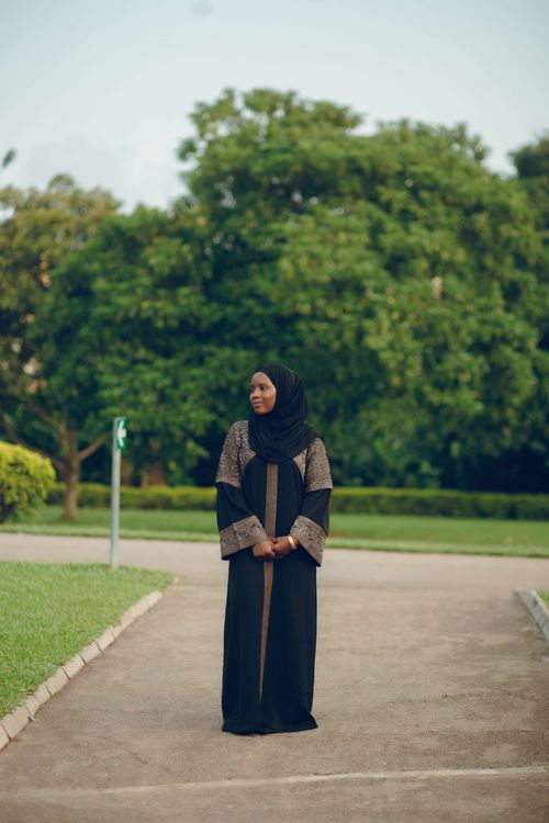 Free Woman in hijab stands outdoors on a pathway with greenery. Stock Photo