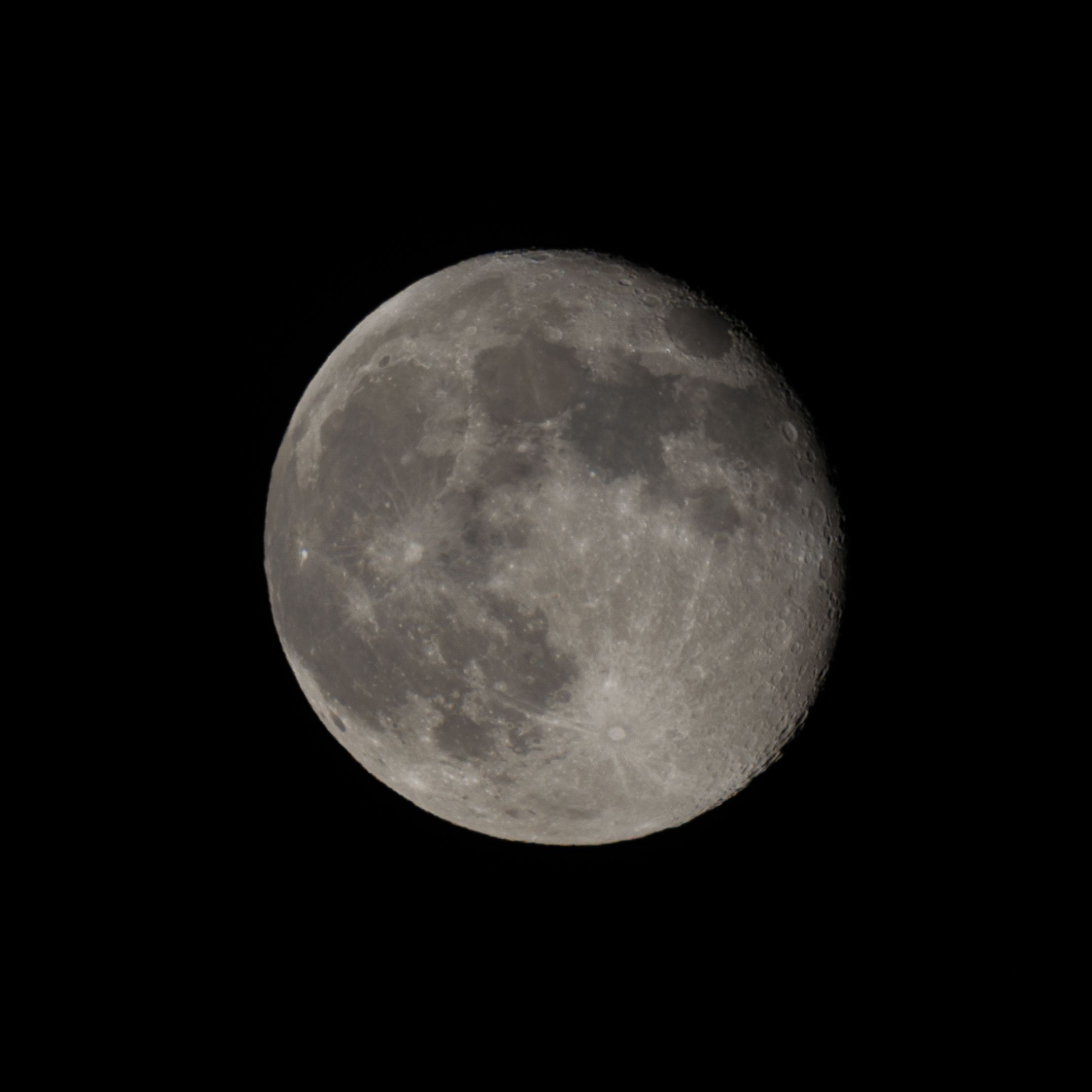 High-resolution photo of the waxing gibbous moon against a black night sky.