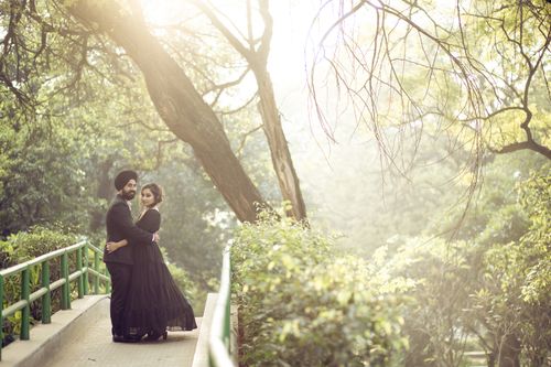 Free A loving couple embraces on a sunlit path surrounded by lush greenery, creating a serene and romantic scene. Stock Photo