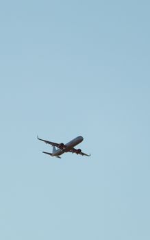 A passenger airplane in flight against a clear blue sky, showcasing aviation travel.