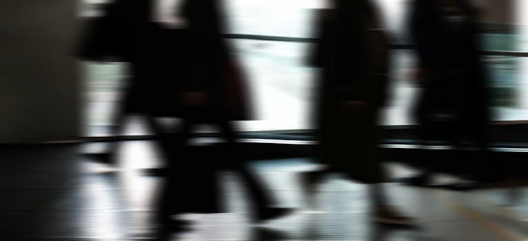 Abstract blurred motion of people walking indoors, depicting urban life and busy routines.