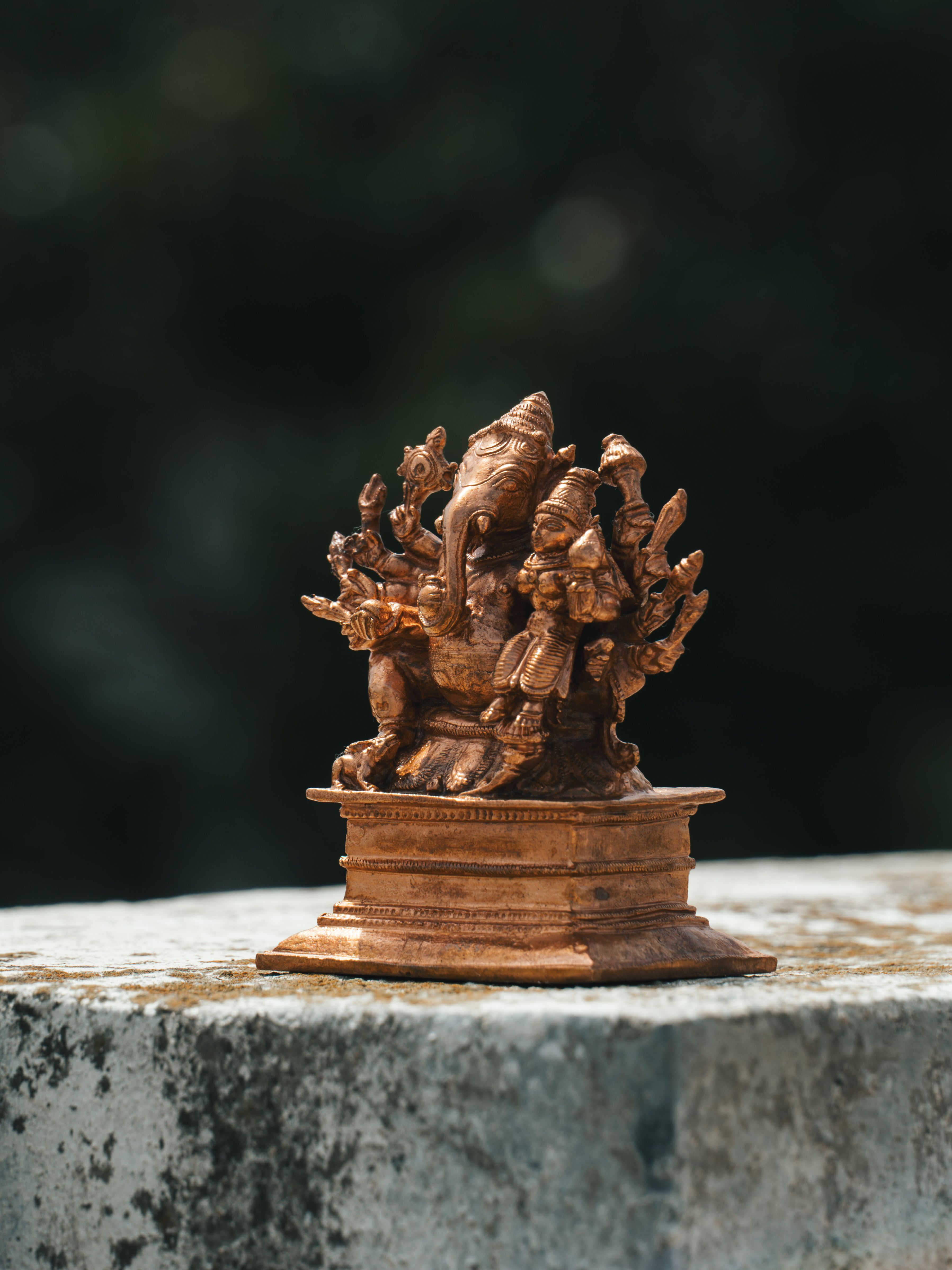 Close-up of an intricately crafted bronze Hindu deity statue on an outdoor surface, showcasing fine artistic details.