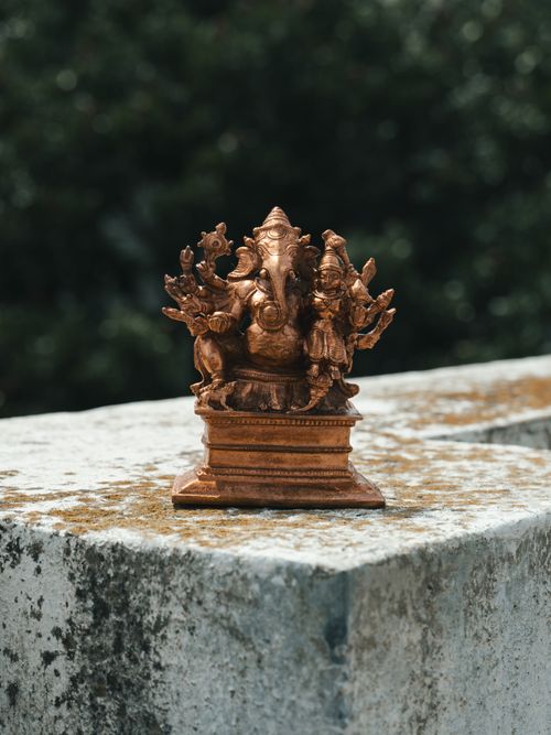 Free Close-up of a detailed bronze Ganesha statue placed on a textured stone surface. Stock Photo