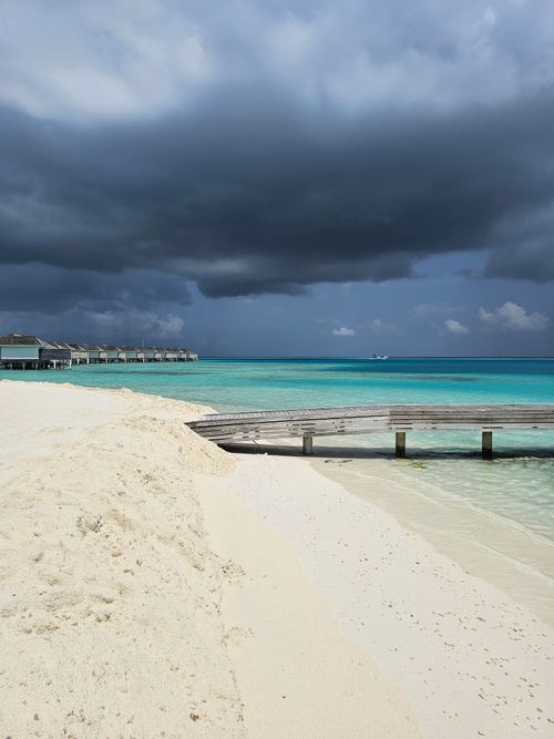 Free Dramatic storm clouds loom over a serene beach in Dhaalu Atoll, Maldives. Stock Photo