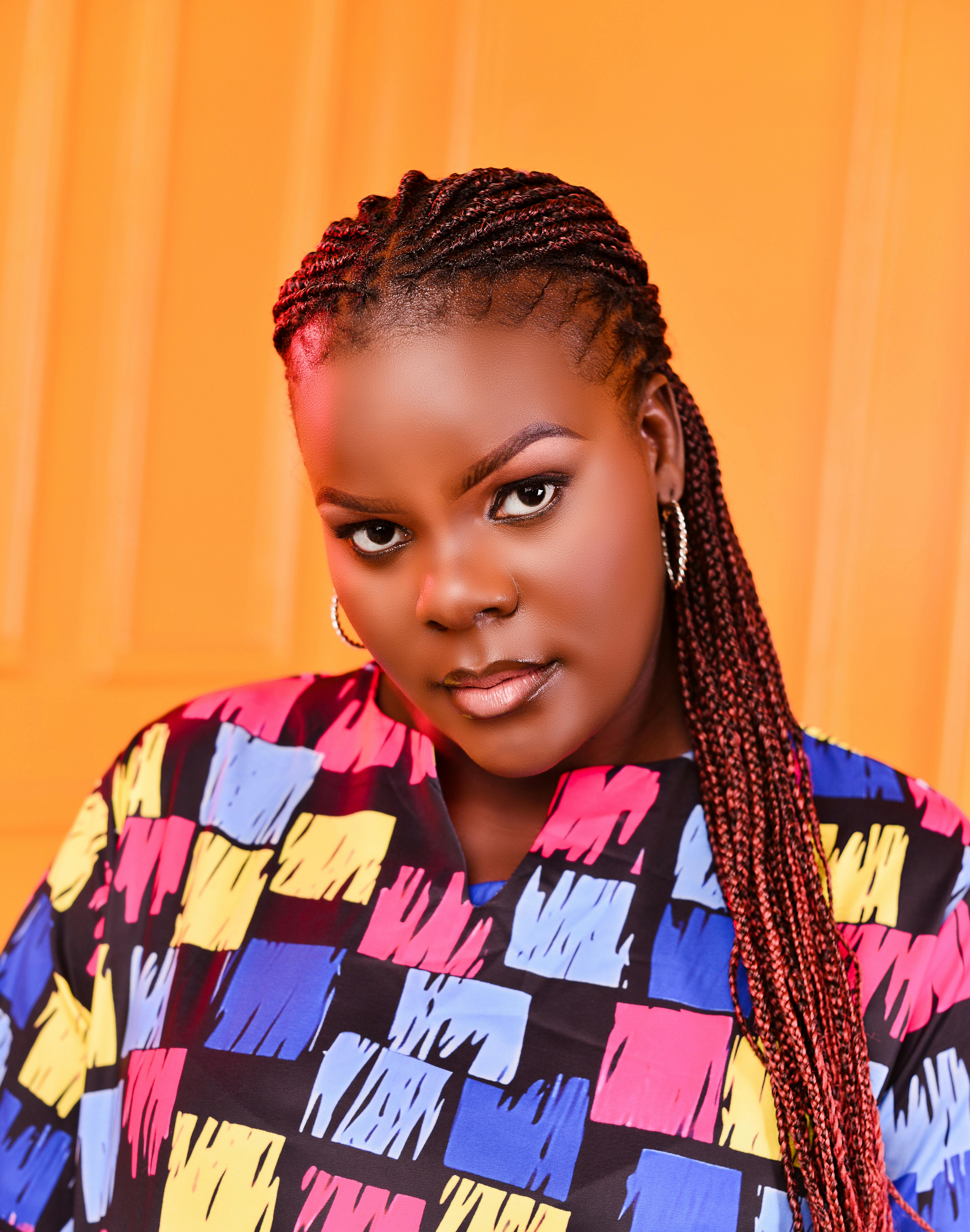 Vibrant portrait of a woman with braided hair against a bright orange background.