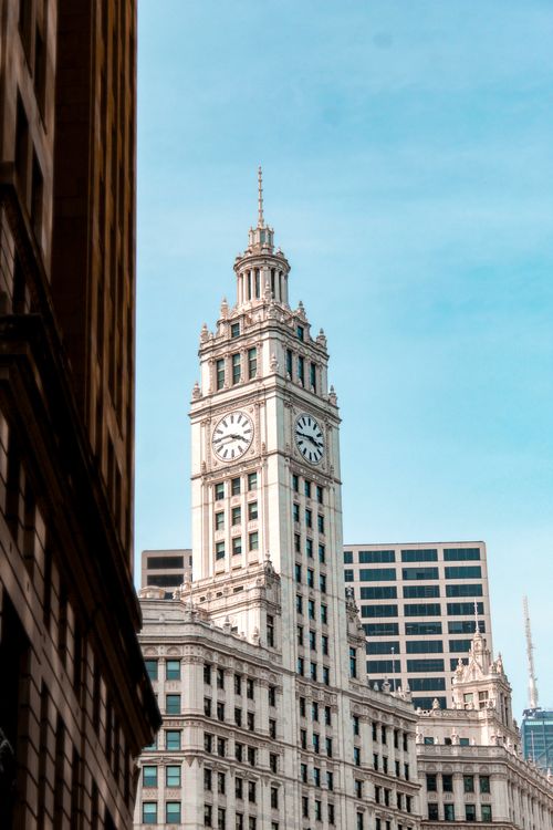 Free View of the iconic Wrigley Building in Chicago surrounded by urban architecture and clear sky. Stock Photo