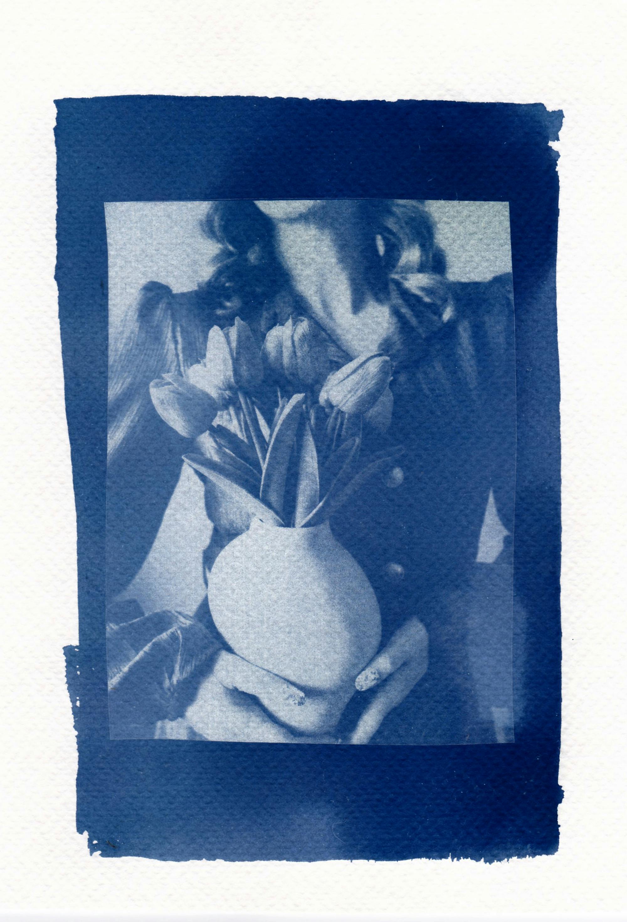 Artistic cyanotype print of a woman holding tulips in a vase, capturing vintage style.