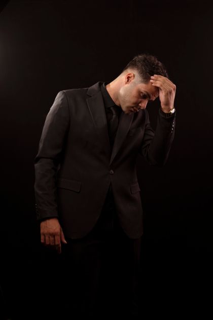 Man in a black suit against a dark background — photo by mohamed abdelghaffar on Pexels