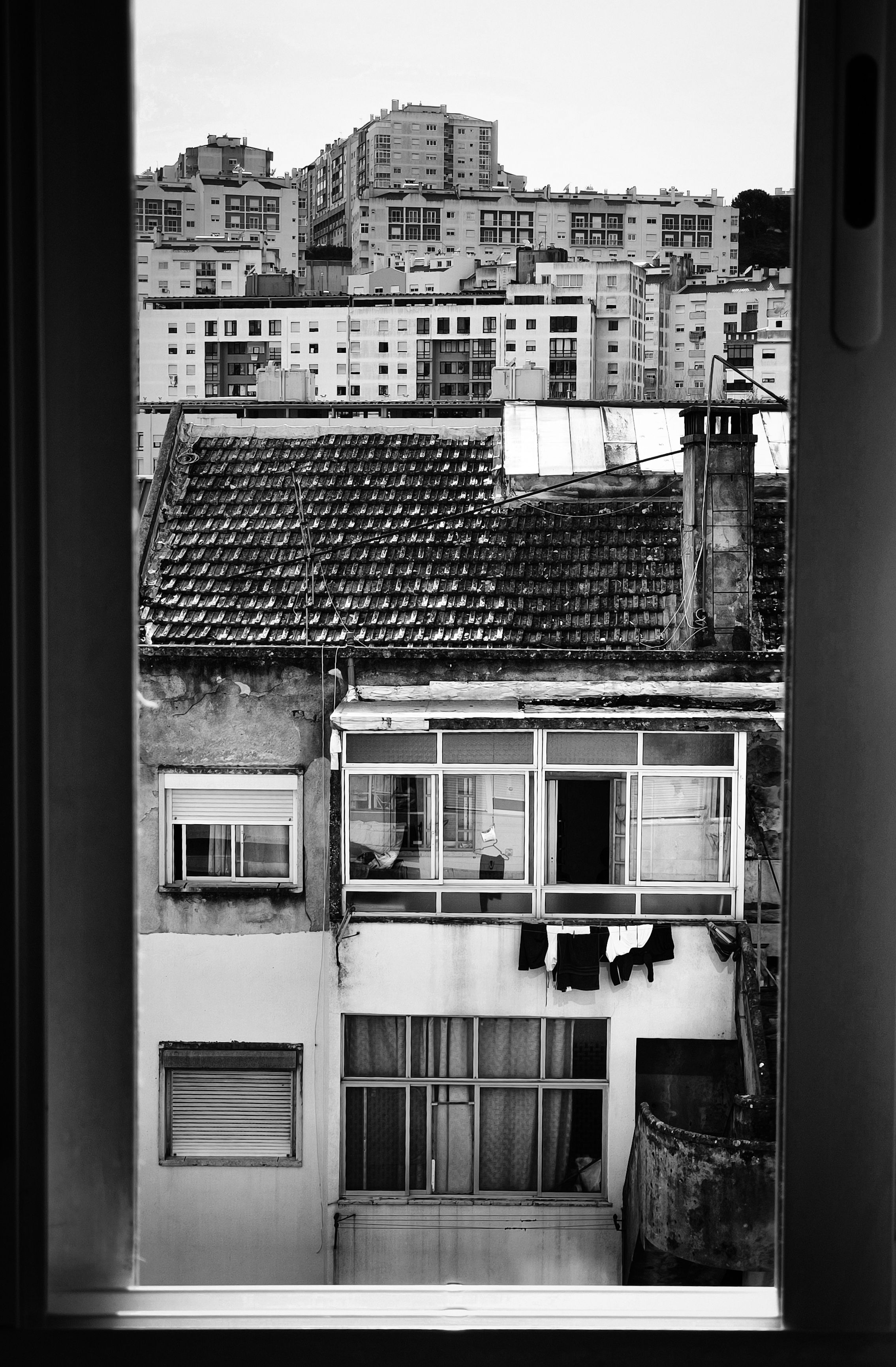 De franc Vista en blanc i negre del paisatge urbà a través del marc d'una finestra que destaca la vida urbana. Foto d'estoc