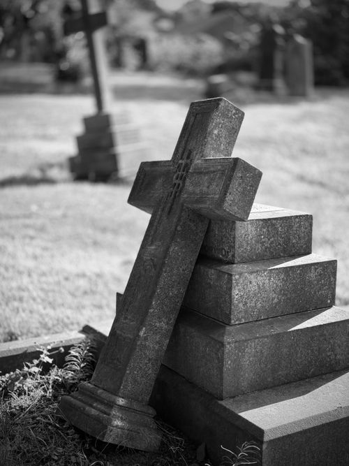 Free A black and white image of a cemetery with a fallen cross gravestone, evoking a sense of history and reflection. Stock Photo