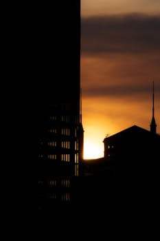 Silhouette of city buildings against a vibrant sunset sky.