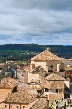 A scenic view of Cuenca's traditional architecture and rolling hills under dramatic clouds.