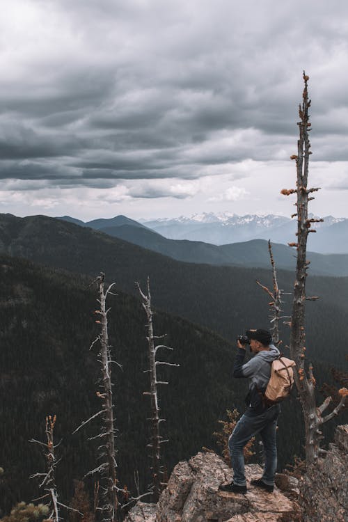 Man On Top Of A Mountain Taking Picture Of The View