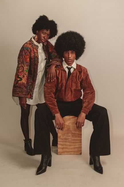 Fotomural Pareja negra con moda inspirada en los años 70, irradiando estilo y confianza en un entorno de estudio.