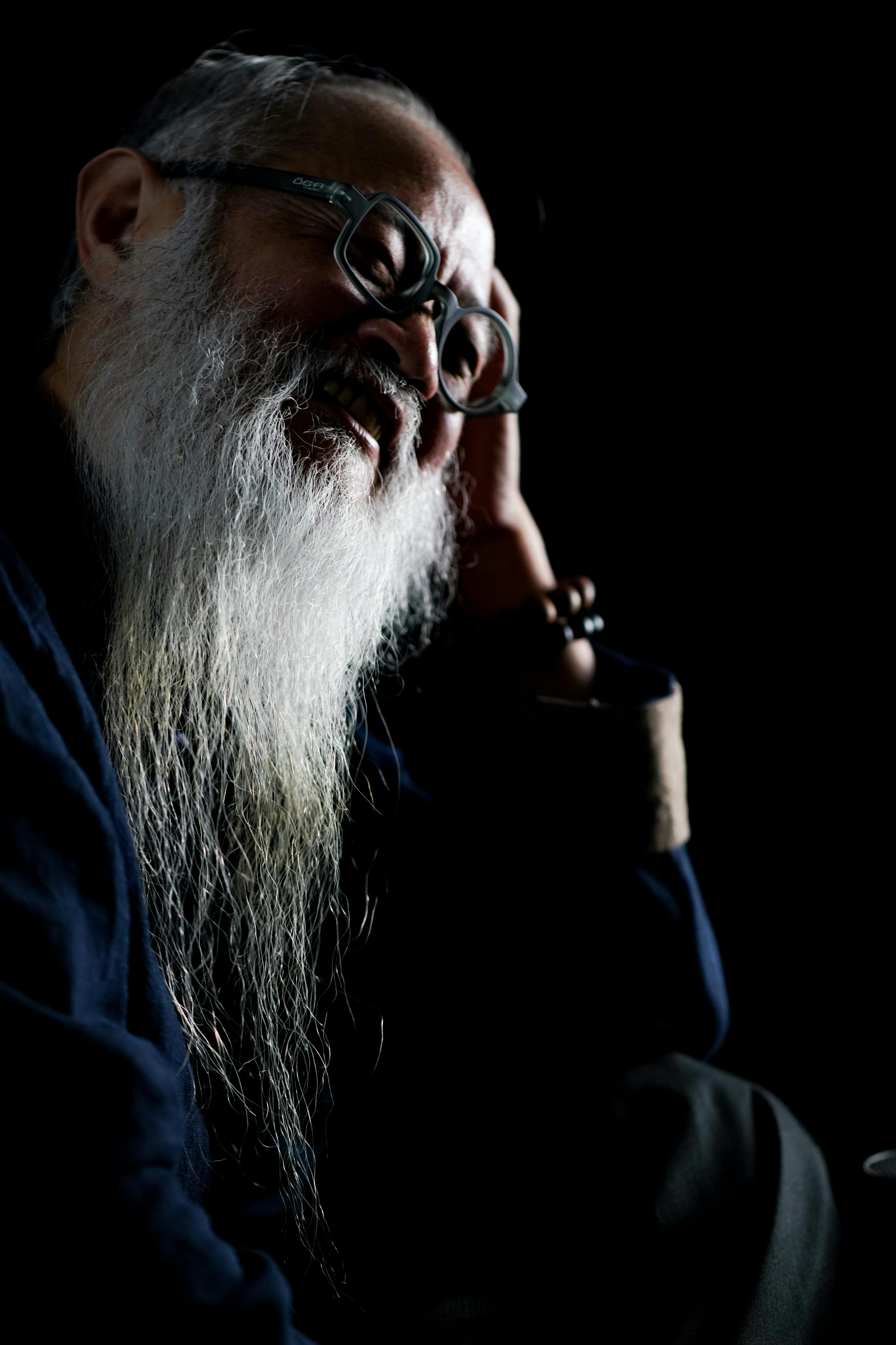 Portrait of a senior man with a long beard in low key lighting, exuding wisdom and contemplation.